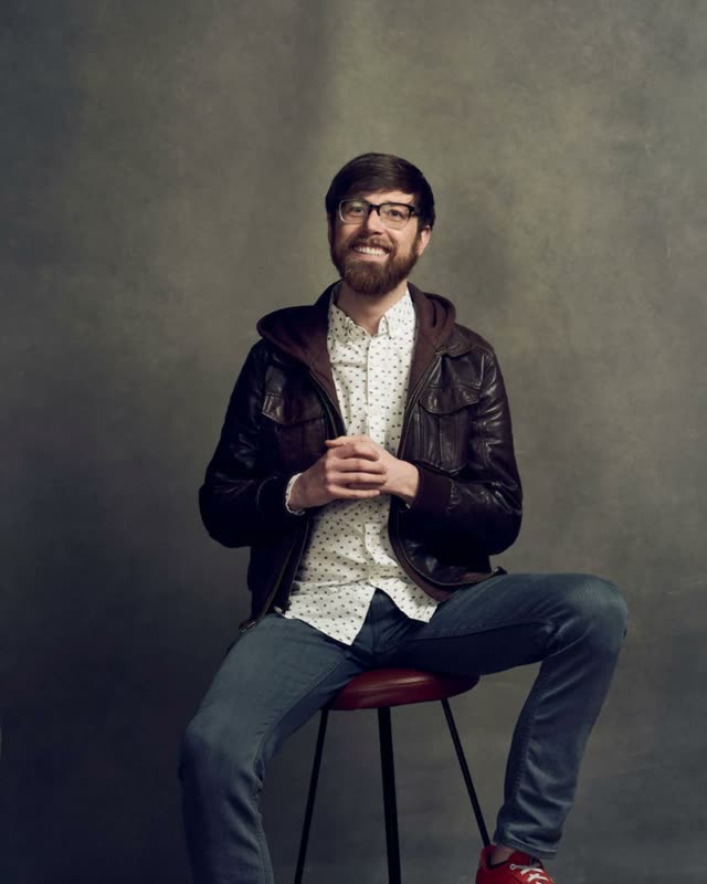 Colton Mulligan headshot: Sitting on a stool in a leather jacket