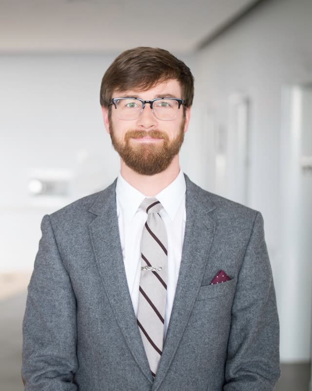 Colton Mulligan headshot: Grey suit and tie