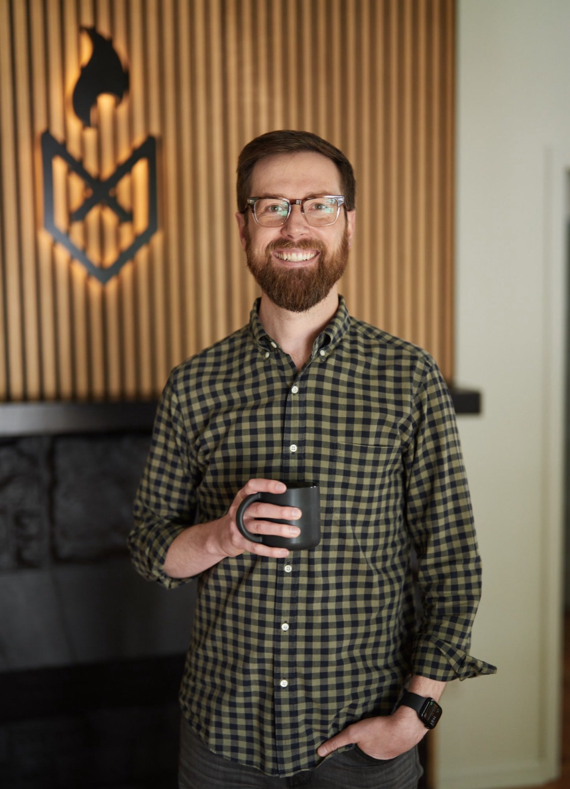 Colton Mulligan standing with a coffee mug in front of the FoxFuel logo