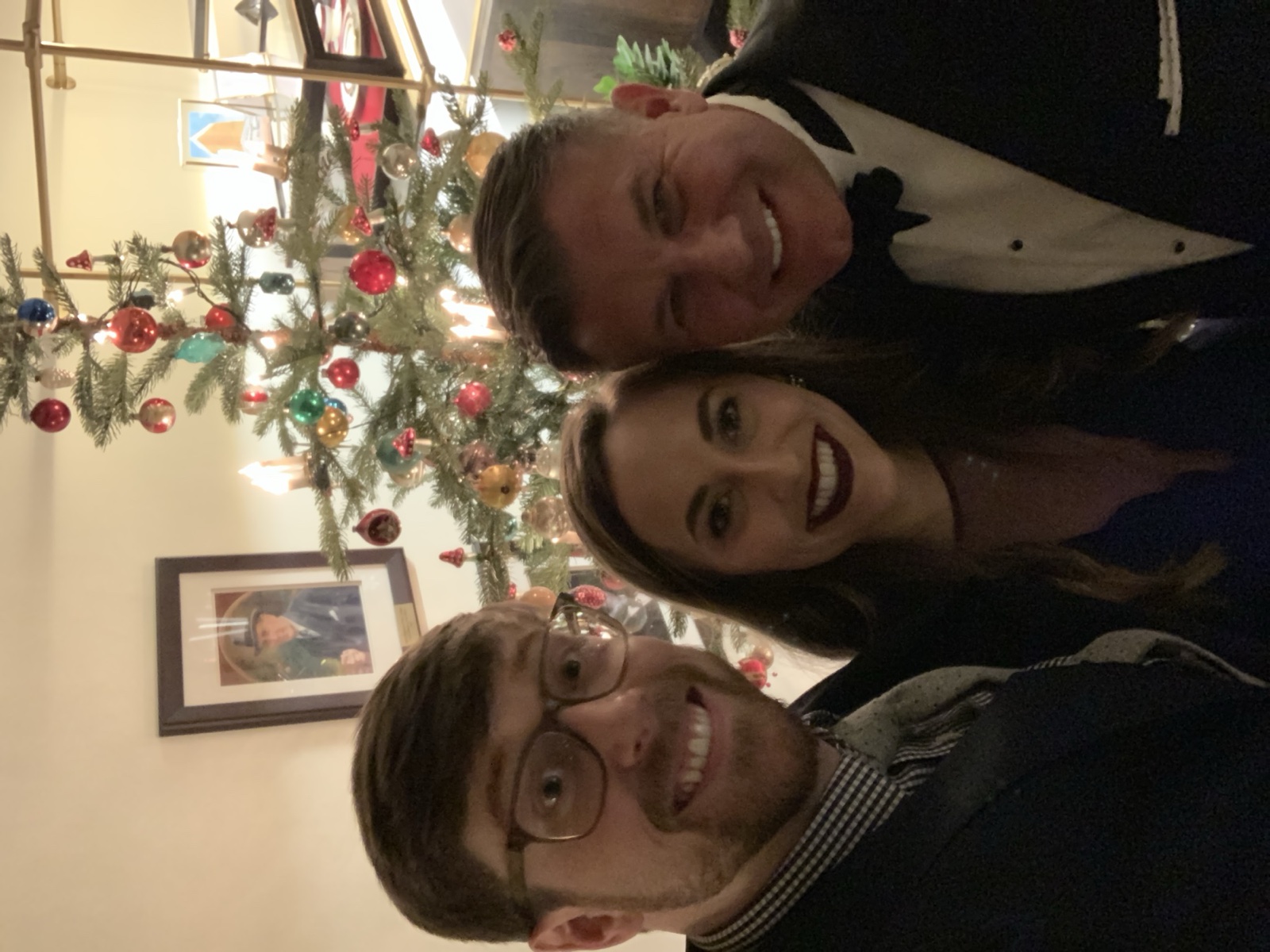 Colton, Aly and Michael Burcham in black tie by a Christmas tree, December 2018
